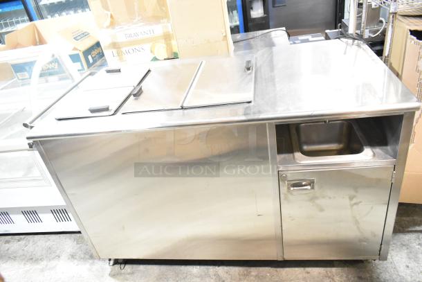 Commercial chest freezer with two center hinge lids and integrated sink bay, stainless steel exterior, in good condition.