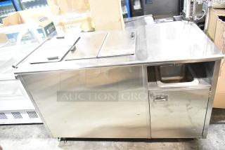 Commercial chest freezer with two center hinge lids and integrated sink bay, stainless steel exterior, in good condition.