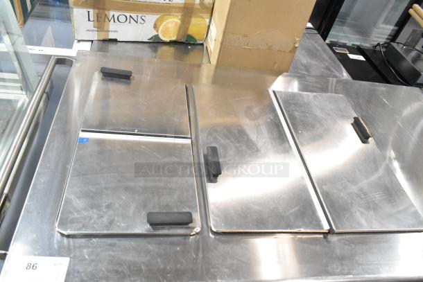 Commercial chest freezer with two center hinge lids and a sink bay, stainless steel surface, used condition.