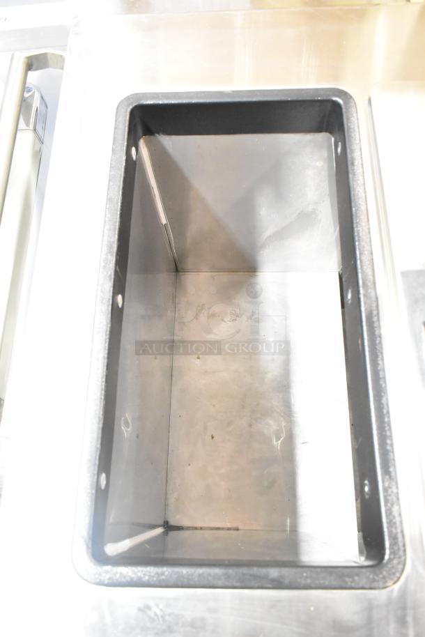 Commercial chest freezer with two center hinge lids, integrated sink bay, stainless steel interior, slight wear visible.