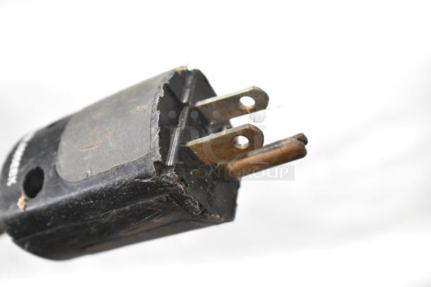A worn electrical plug with visible metal prongs and a damaged black casing.