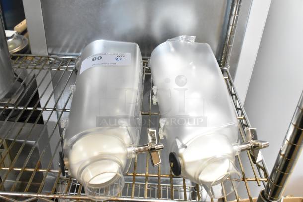 Two clear poly dry food dispenser hoppers on a metal shelf, each with a dispensing mechanism and a label indicating auction details.