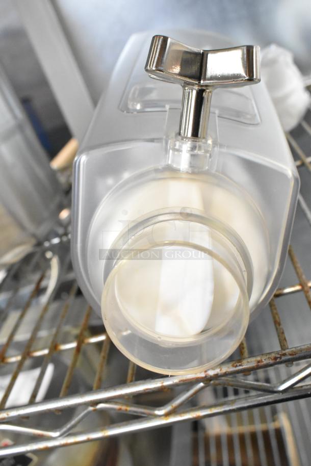 Clear poly dry food dispenser hopper with chrome handle, in good condition, on metal shelving.