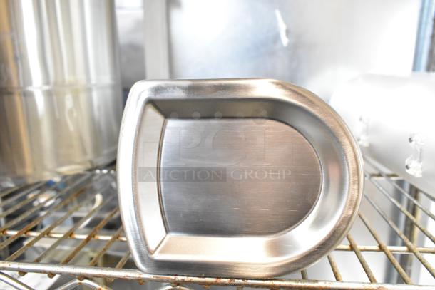 Two clear poly dry food dispenser hoppers shown on a metal shelf, featuring a stainless-steel door, in good condition.