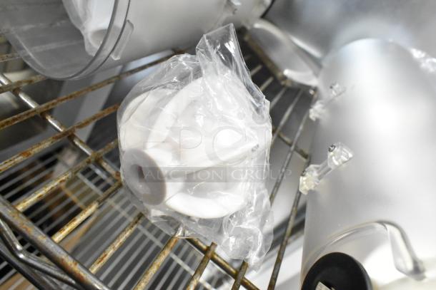 Two clear poly dry food dispenser hoppers on a metal shelf, partially wrapped in plastic. In good condition.