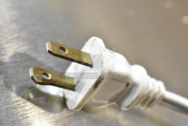 Close-up of a white 120-volt plug for a Cuisinart HandyPrep 3 Cup Food Processor against a metallic surface.