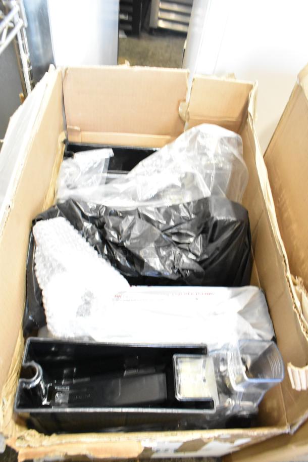 Box containing various items, including dry food dispenser hoppers, in packaging; condition and contents unspecified.