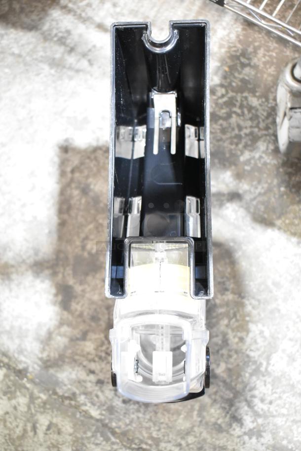 Dry food dispenser hopper in black and clear plastic, showing top view of inner mechanisms; part of mixed auction lot.