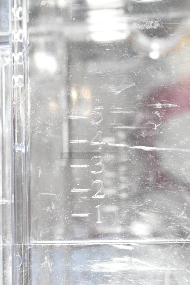 Clear plastic hopper with measurement markings from 1 to 5, suitable for dry food dispensing, in used condition.