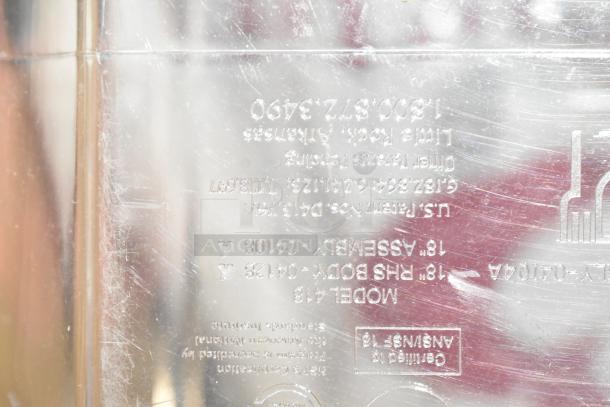 Close-up of a metal surface with etched text, showing manufacturing details and model number. Scratches visible.