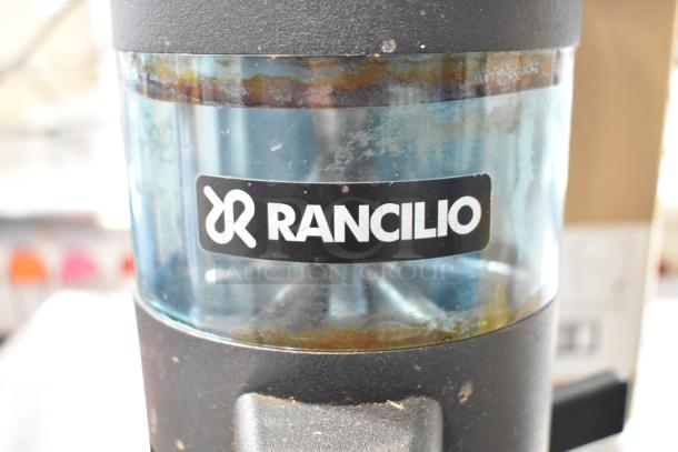 Rancilio MD 50/AT espresso bean grinder, commercial grade. Visible wear on clear and black body. Rancilio branding shown. 110 Volts, 1 Phase.