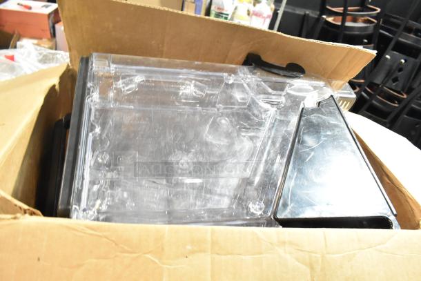 Box containing seven clear poly dry dispenser hoppers, stacked and visible. Used condition with visible wear.