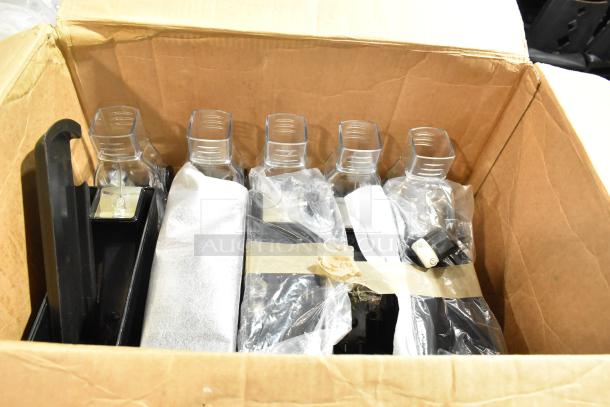 7 Poly Dry Dispenser Hoppers in box. Clear plastic tops, black bases, some wrapped in plastic. New condition visible.