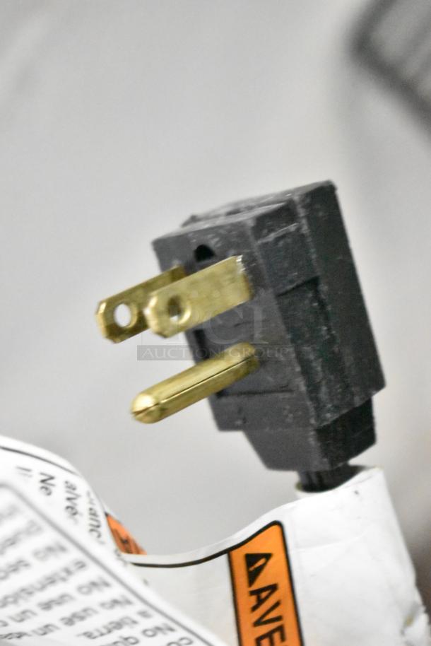 Close-up of a power plug for a Whirlpool WRR56X13FW02 Reach In Cooler, 115V, 1 Phase, with warning labels attached.
