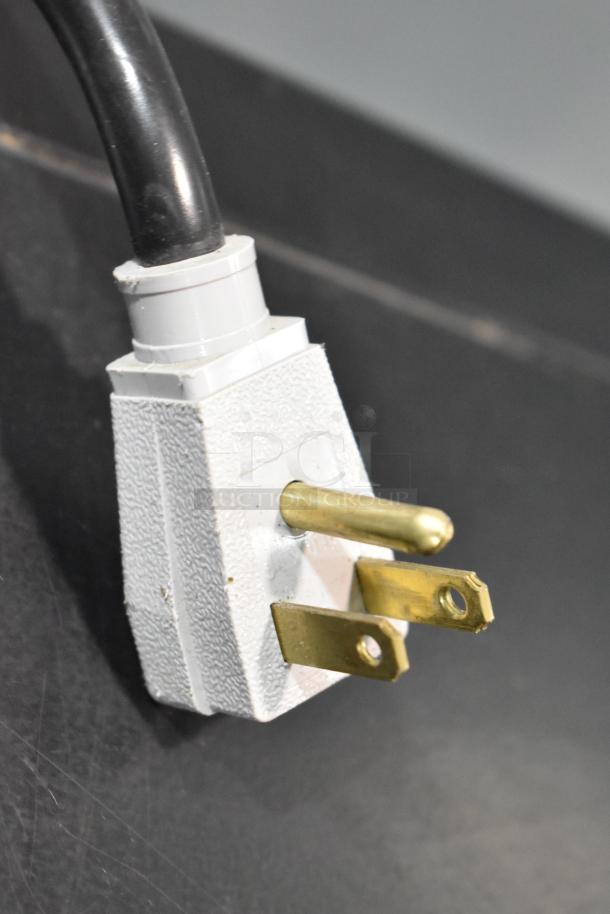 Close-up of a 115-volt electrical plug from a True GDM-41SL-48-HC-LD cooler, showing prongs and textured casing.