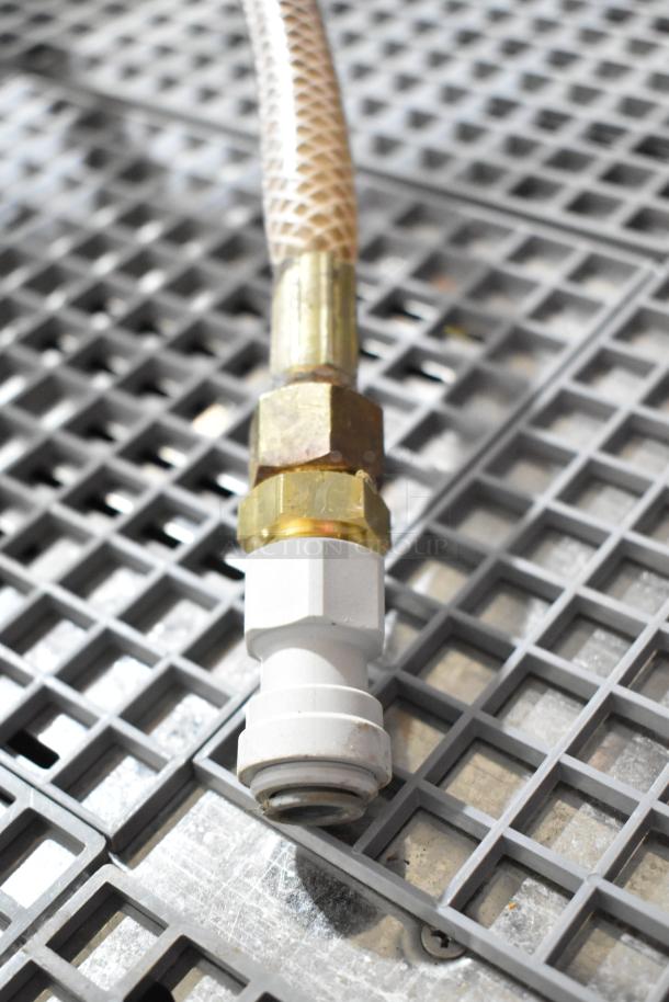 Close-up of a hose fitting, part of the Nuova Simonelli Aurelia II espresso machine. Brass connectors visible.