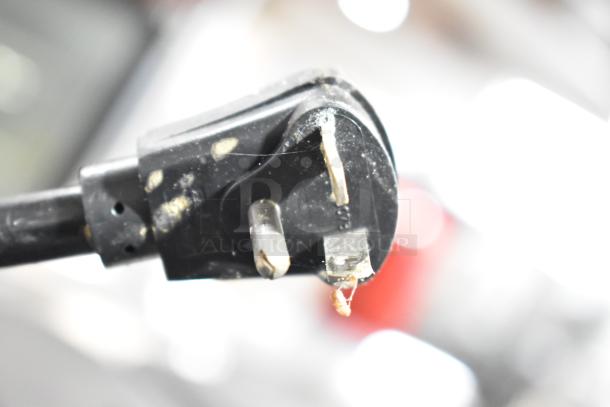 Close-up of worn appliance plug with visible damage on prongs and black casing, likely from an Electro Freeze ice cream machine.