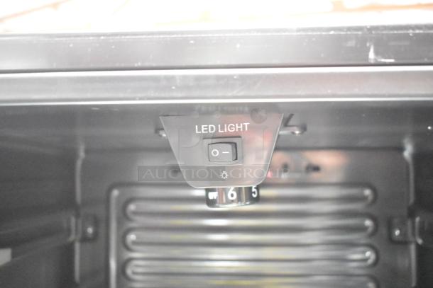 LED light switch inside Midea MRV115S1BST beverage cooler. Black panel with on/off LED control and temperature dial.
