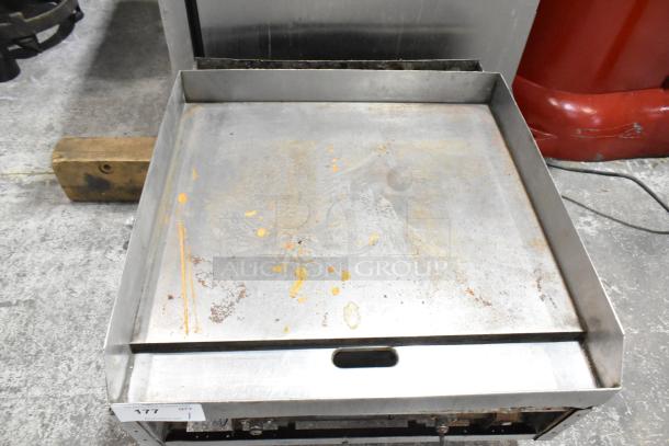 Commercial countertop gas-powered flat top griddle with signs of use, featuring a large cooking surface and sturdy construction.