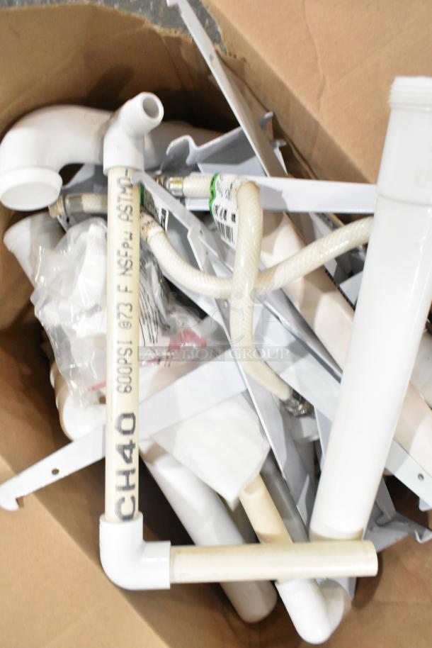 Lot of various plumbing items including brackets, lid, extension tubes, hose, and white plastic pipes with markings.