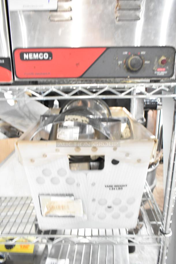Lot of various items in a crate including brackets, lid, extension tubes, and hose. Visible Nemco food warmer above.