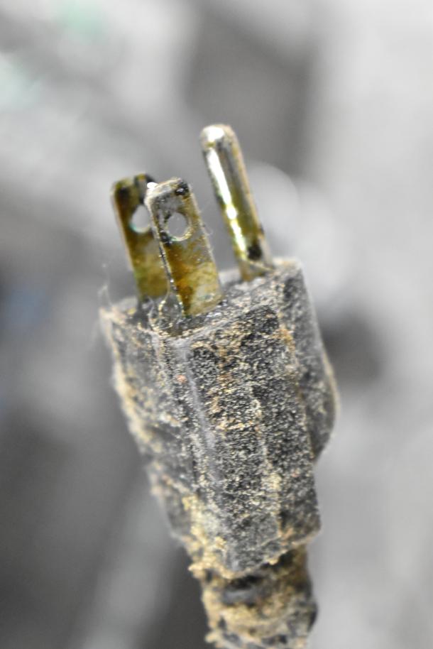 Close-up of a damaged power plug for a Nemco 6055A Commercial Countertop Food Warmer. Burn marks and dust visible.
