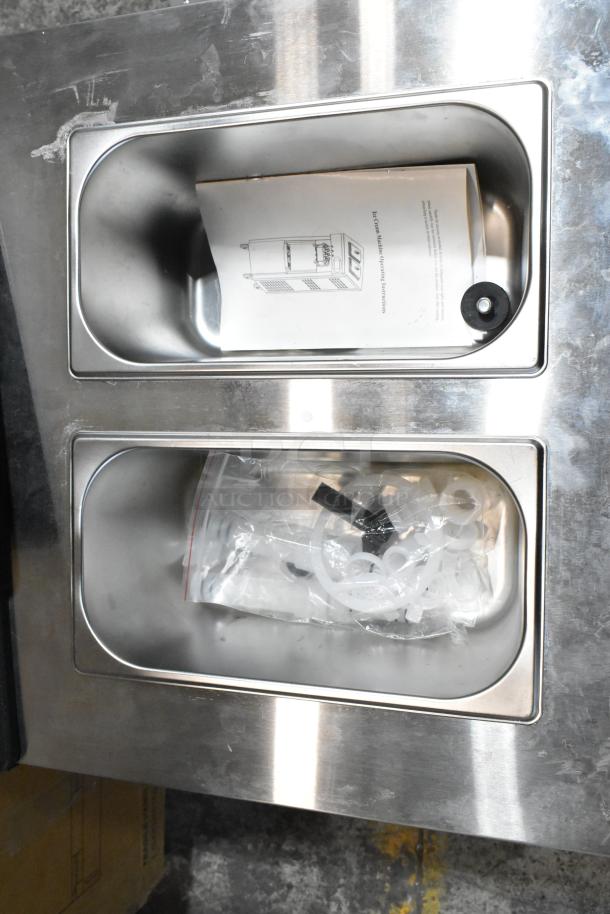 Vevor YKF-8218T ice cream machine accessories in bins; manual and small parts visible.