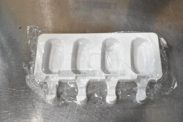 Brand new popsicle molds, white plastic, four cavities, unopened, slight surface scratches, packaged in plastic wrap.