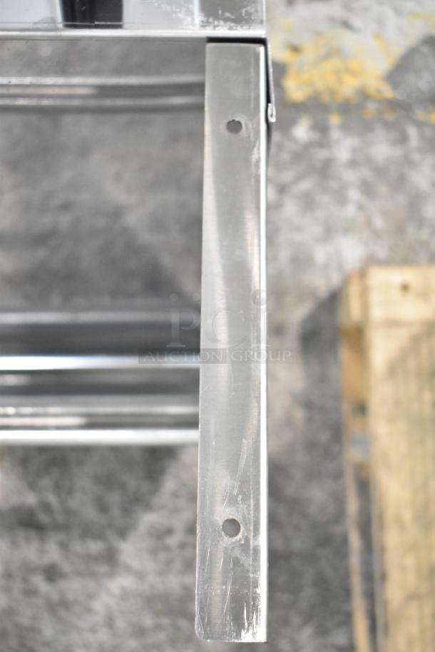 Metal wall mount shelf bracket with drilled holes, visible surface wear, suitable for industrial use.