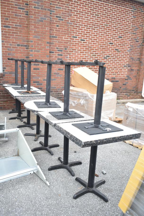 13 various dining height tables with metal bases and patterned tops, in good condition, stacked outdoors.