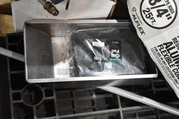 Pallet of mixed items including metal pans, grill pad, labeled Alflex aluminum conduit, on a plastic grid base.