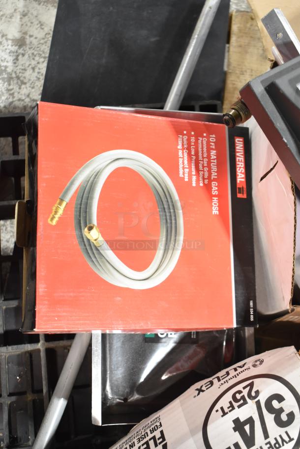 Auction pallet with various items including a Universal 10ft natural gas hose in original packaging.