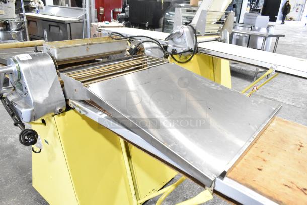 Rondo Seewer reversible dough sheeter, commercial floor model, yellow base, metal rollers, moderate wear, power cord attached.