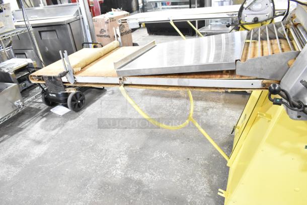 Rondo Seewer commercial floor style reversible dough sheeter in good condition, features adjustable sheeting surfaces with sturdy yellow base.