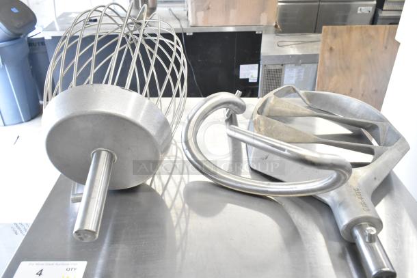 Varimixer V80A attachments including whisk, dough hook, and paddle, shown on a metal surface.