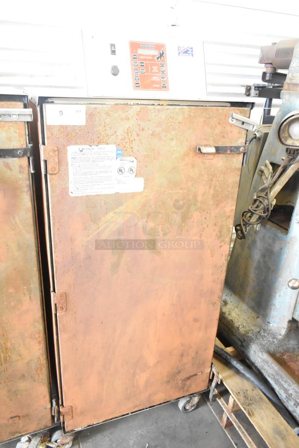 Cookshack 250 commercial electric smoker cabinet on casters, showing signs of rust. 208 volts, control panel visible.