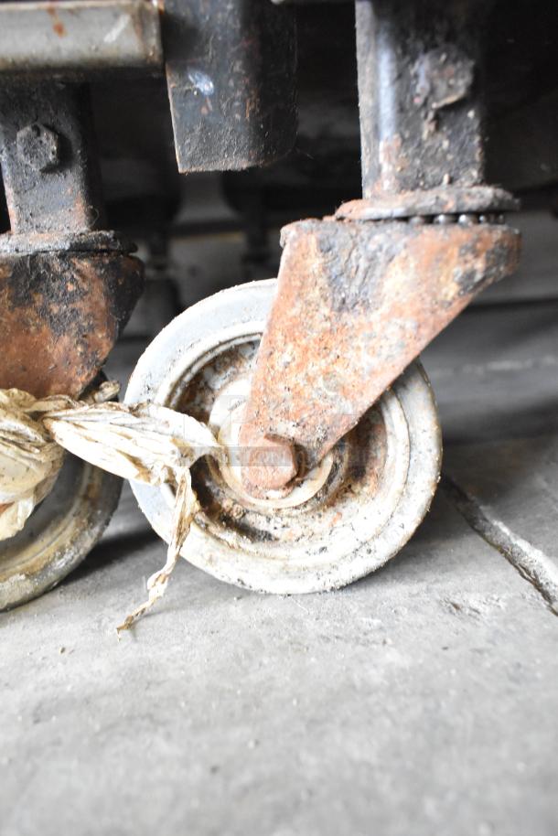 Rusty caster wheel of a Cookshack 250 Commercial Electric Smoker Cabinet, condition indicates wear.