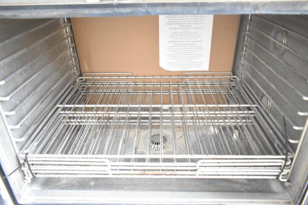 Interior of Blodgett HVH-100E HydroVection oven, showing new wire racks, stainless steel interior, and warranty label.