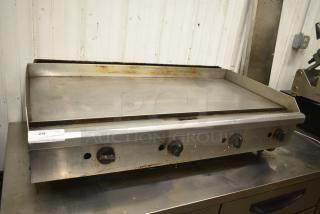 Commercial countertop gas-powered flat top griddle with three control knobs. Used condition, visible wear on surface.