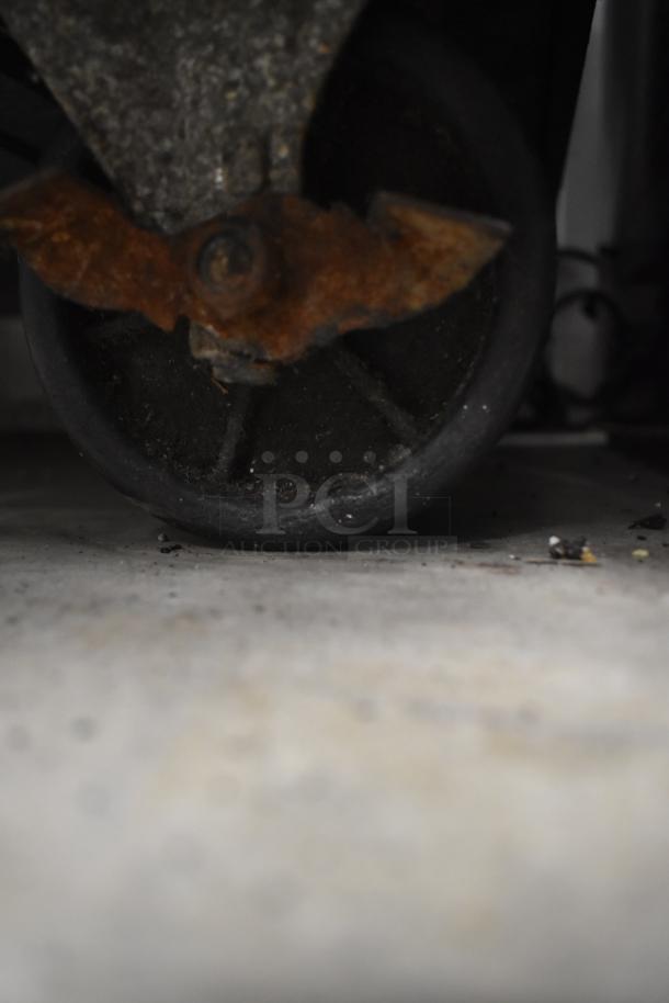 Rusty caster of Padela Commercial 4 Drawer Chef Base, indicating wear. 115 Volts, 1 Phase, on commercial casters.