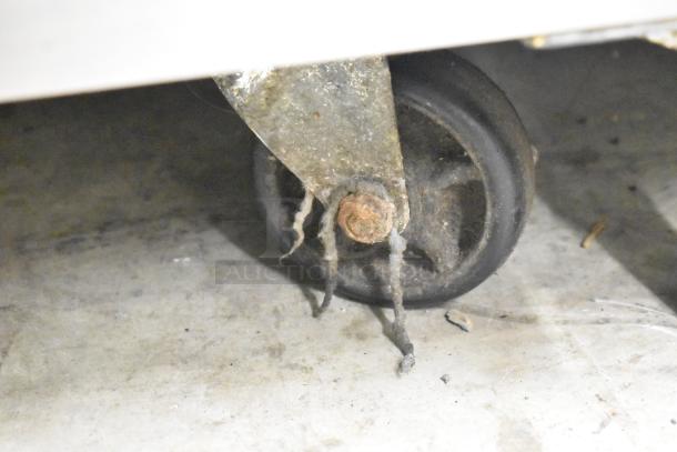 Close-up of a worn caster wheel on a Cooler Depot UUC-72R-E-HC commercial undercounter cooler.