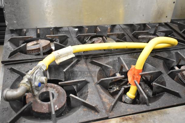 Therma-tek TMD36-6-1N commercial 6 burner range with oven, natural gas, shown with yellow gas line and metal backsplash.