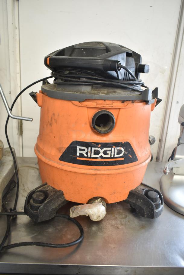Rigid HD16000 Wet Dry Shop Vac, 120V, 1 Phase. Orange body, dirt marks visible. Logo on front, used condition.