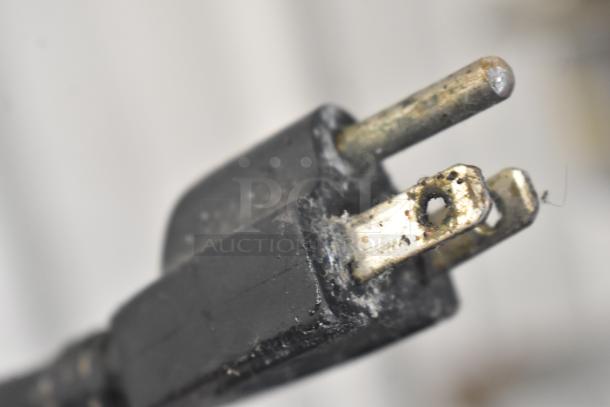 Close-up of a worn, two-prong electrical plug associated with a BakeMax BMPME20 mixer, showing signs of use.