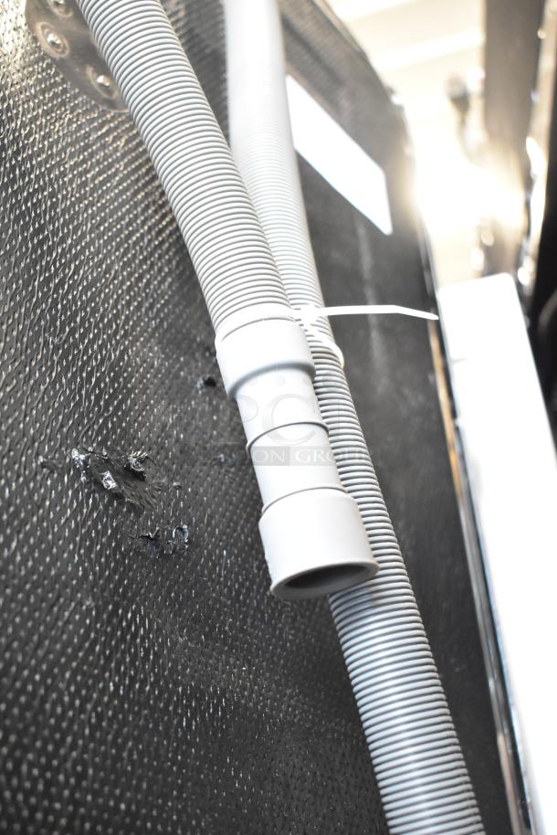 Back view of a 2025 Honeywell HDS24SS-H 24" dishwasher, showing gray hose, plastic tub, and minor scratches.