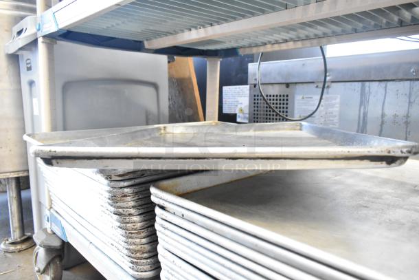 Stack of 31 various baking and roasting pans in used condition, including full-size baking pans. Auction lot.