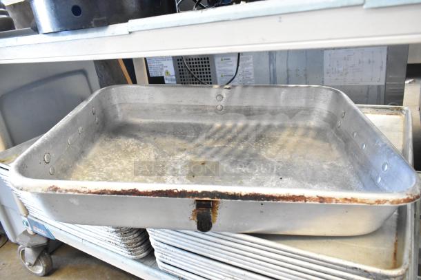 Stack of full-size aluminum baking pans and a roasting pan with visible wear, ideal for bulk purchase.