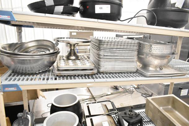 Assorted kitchen items on shelves include metal bowls, baking pans, muffin trays, and colanders. Condition varies.