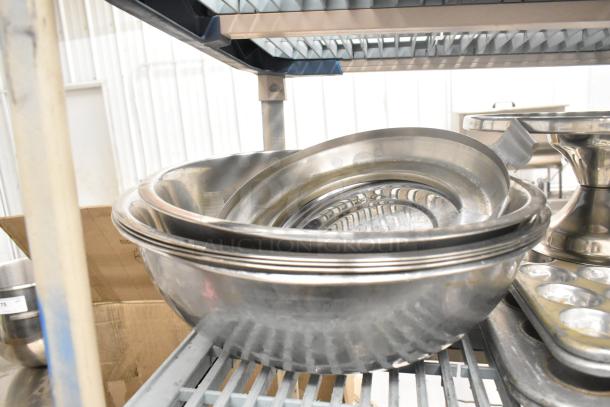 Metal kitchenware set with bowls, baking pans, muffin pans, and colanders on a shelf, used condition. 38 pieces total.