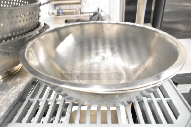 Alt text: Stainless steel mixing bowl among various kitchenware including colanders and pans, part of 38-item auction lot.